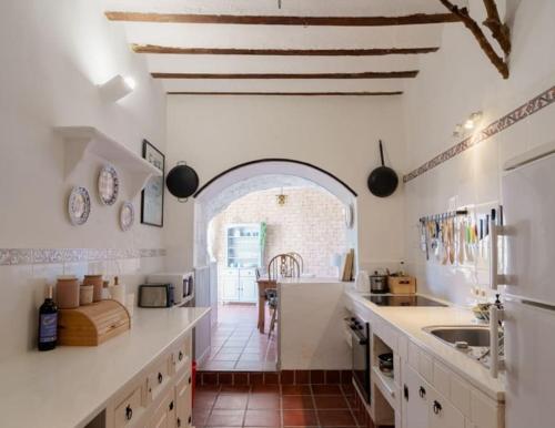 a kitchen with white counters and an arched doorway at Casa rural con jacuzzi y chimenea en paraje único - La Casa del Pino in Blanca