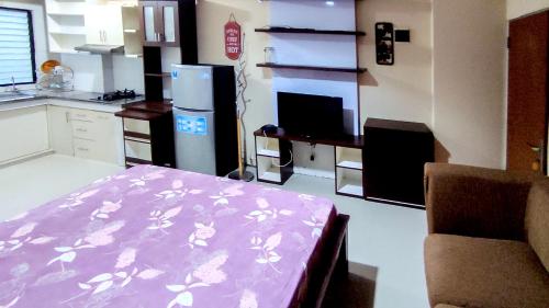 a living room with a kitchen with a refrigerator and a table at Lily Room at Apartment Cibubur Village in Cibubur