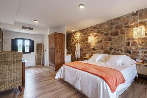 ein Schlafzimmer mit einem großen Bett und einer Steinmauer in der Unterkunft DUO SOMNIA, suite con jacuzzi y chimenea, only adults 