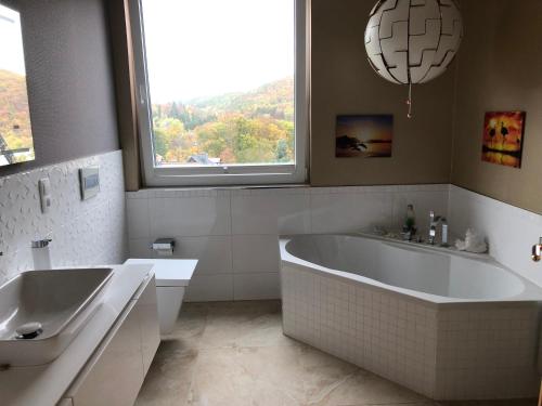 a white bathroom with a tub and a sink at Haus Brockenblick in Wernigerode