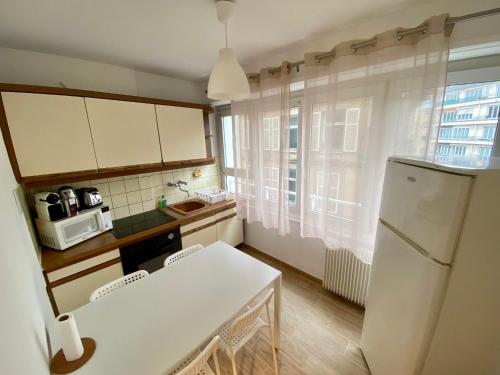 a kitchen with a table and a white refrigerator at Appartement Gare Strasbourg Parking in Strasbourg