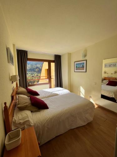 ein Hotelzimmer mit einem großen Bett und einem Fenster in der Unterkunft Apartamentos SNÖ Cerler in Aramón Cerler