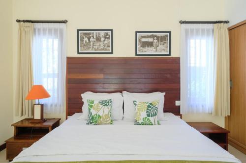 a bedroom with a large white bed with two windows at Dinar Hills Ungasan in Nusa Dua