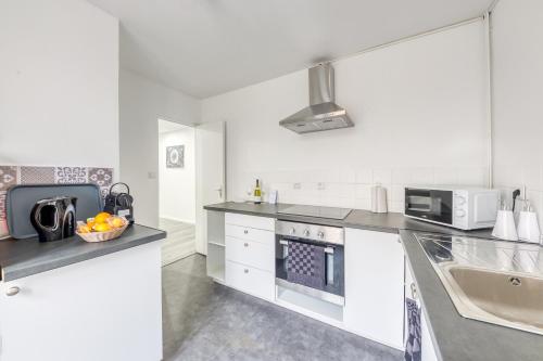 une cuisine blanche avec un évier et un micro-ondes dans l'établissement J Mo Home - Tonnerre - O' Verre, à Tonnerre