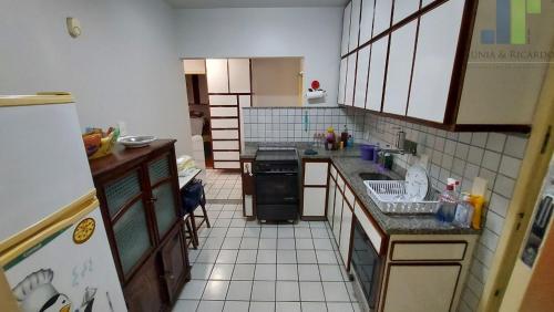 małą kuchnię z białą podłogą wyłożoną kafelkami w obiekcie Apartamento confortável no centro de Guarapari w mieście Guarapari