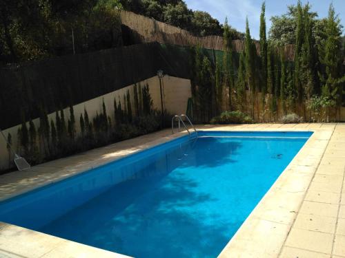 a blue swimming pool in front of a fence at Magnífico chalet entre Sierra Nevada y Granada in Dúdar