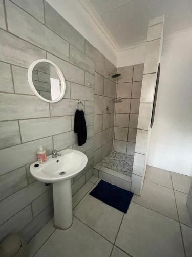 uma casa de banho branca com um lavatório e um chuveiro em De Anker Verblyf em Olifantshoek