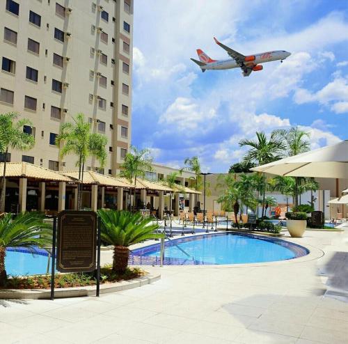 um avião está voando sobre uma piscina com um hotel em Apartamentos Boulevard em Caldas Novas