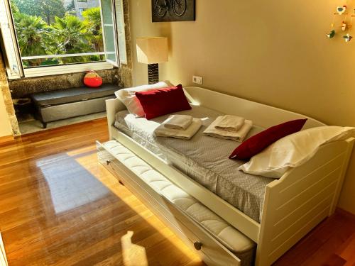 una cama con almohadas rojas en una habitación en RESIDENCIAL MONDARIZ BALNEARIO 118, en Mondariz-Balneario