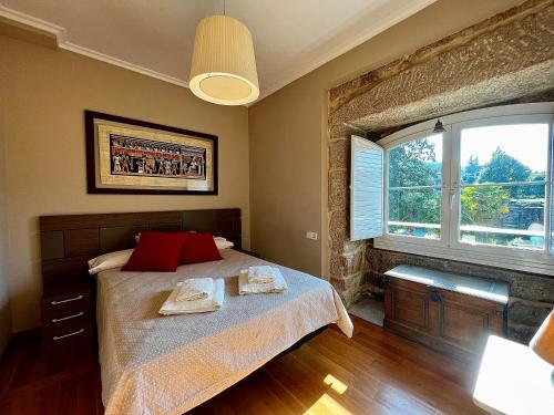 Un dormitorio con una cama con almohadas rojas y una ventana en RESIDENCIAL MONDARIZ BALNEARIO 118, en Mondariz-Balneario