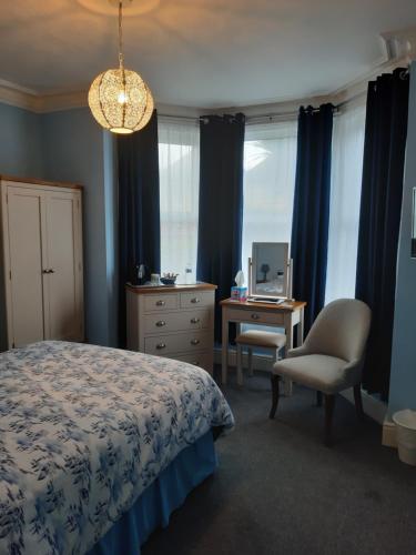 una camera con letto, scrivania e sedia di South Rising Guest House a Poole