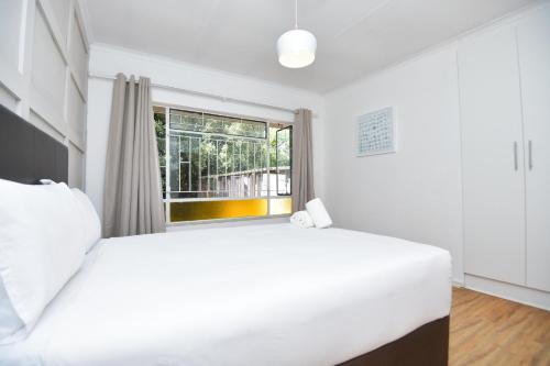 a bedroom with a large white bed and a window at Spacious Menlyn Maine Villa in Pretoria