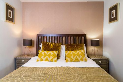 a bedroom with a bed with yellow pillows and two lamps at Goodramgate Apartments in York
