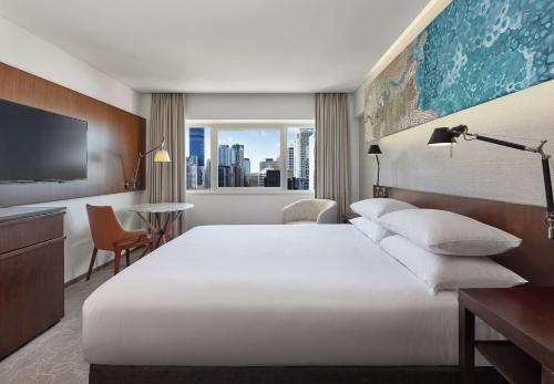 a hotel room with a large white bed and a window at Hyatt Regency Brisbane in Brisbane