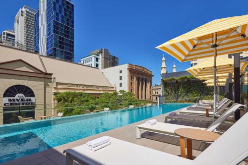 a swimming pool with tables and umbrellas on a building at Hyatt Regency Brisbane in Brisbane