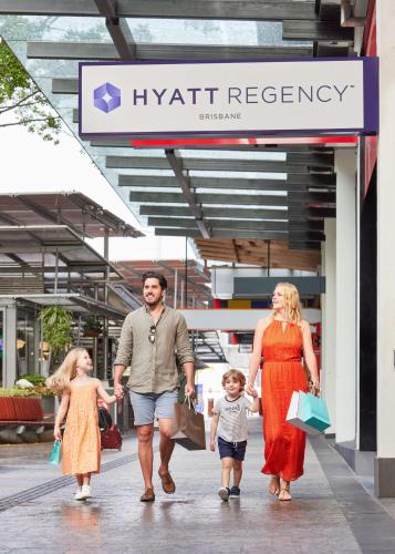 a man and woman and two children walking down a sidewalk at Hyatt Regency Brisbane in Brisbane