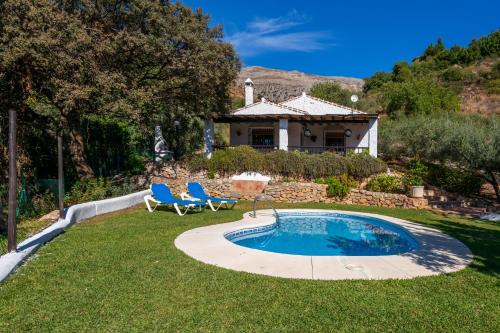 a yard with a pool and two chairs and a house at El Chorro Villas Casa Adelfa in El Chorro