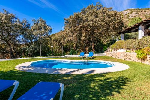 een zwembad met blauwe stoelen in een tuin bij El Chorro Villas Casa Adelfa in El Chorro