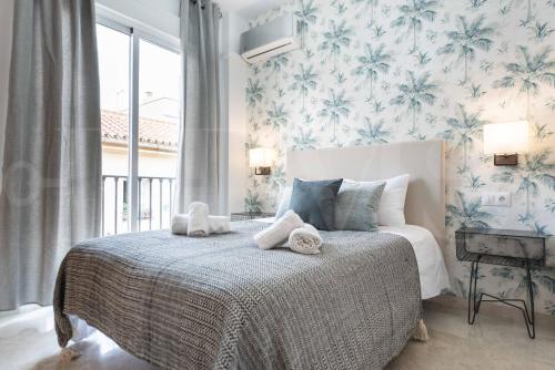 een slaapkamer met een bed met blauw en wit behang bij Lovely duplex with private parking near city center by REMS in Málaga