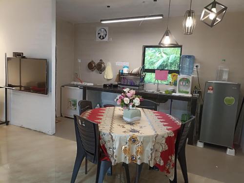 - une salle à manger avec une table et des fleurs dans l'établissement Haji Ineng Homestay- Guest House, à Kota Samarahan