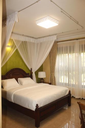 1 dormitorio con 1 cama grande y cortinas blancas en Terezina Guest House and Homes Pakwach, en Pakwach East