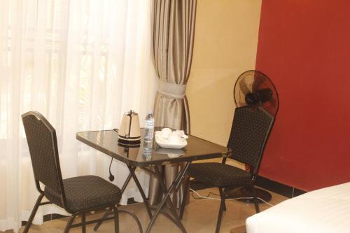 un tavolo e sedie in una camera con un letto di Terezina Guest House and Homes Pakwach a Pakwach East