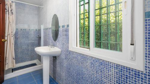 baño de azulejos azules con lavabo y ventana en Casa Rural La Milla Verde Málaga - Campanillas by Ruralidays en Málaga