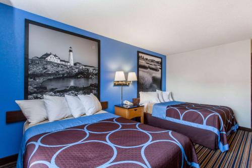 a hotel room with two beds and a picture on the wall at Super 8 by Wyndham Lewiston Auburn Area in Lewiston