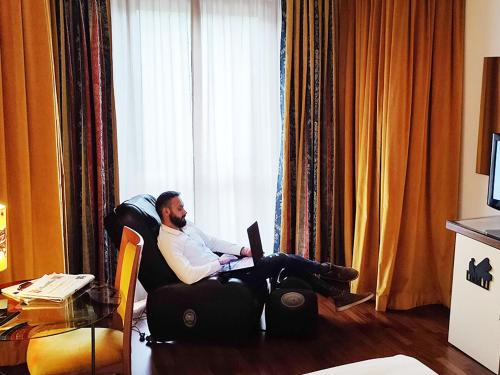 a man sitting on a chair in a living room at Hotel Giò Wine e Jazz Area in Perugia