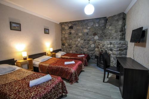 a hotel room with two beds and a stone wall at Hotel Svaneti in Mestia