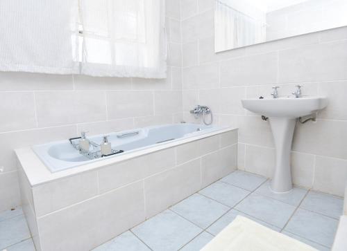 a white bathroom with a tub and a sink at Spacious Menlyn Maine Villa in Pretoria