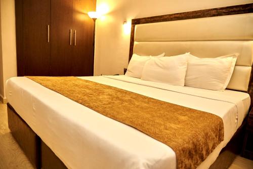 a bedroom with a large bed with white sheets and pillows at MayFair Hotel Maitama Abuja in Abuja
