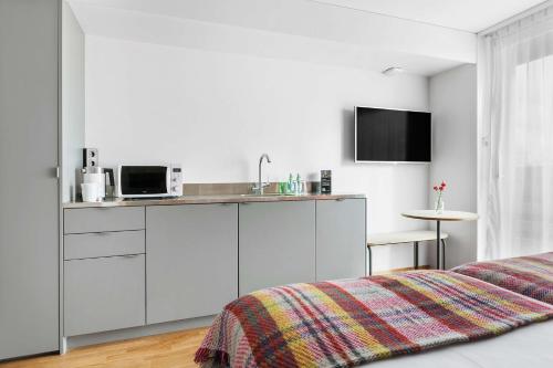 a white bedroom with a bed and a kitchen at Best Western Plus Ten Hotel in Upplands-Väsby