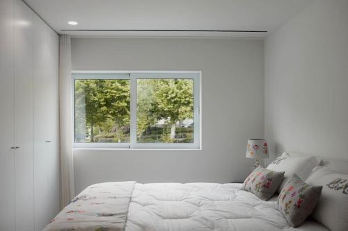 um quarto branco com uma cama e uma janela em Lucy's House em Lousada