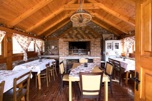 een eetkamer met tafels en stoelen en een open haard bij River Side in Aljmaš