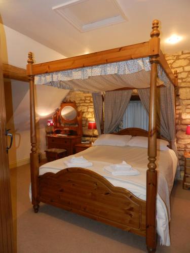 a bedroom with a canopy bed in a room at Cotswold Charm Stable Cottage in Chipping Campden