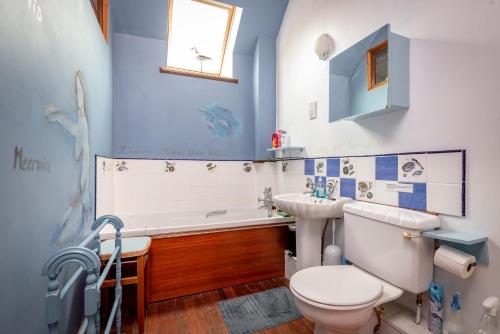 a bathroom with a toilet and a tub and a sink at The Granary - Quaint & Cosy Cottage in Boarhills