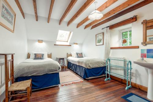 a bedroom with two beds and a sink in it at The Granary - Quaint & Cosy Cottage in Boarhills