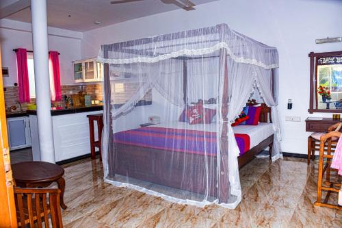 a bedroom with a bed with a canopy at Indika's Apartment in Hikkaduwa