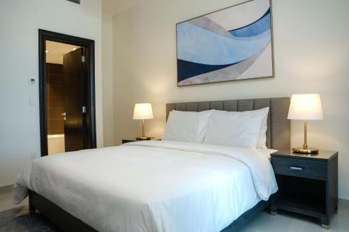 a bedroom with a large white bed with two lamps at Abdali Views Apartments in Amman