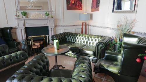 a living room with leather couches and a table at The Belgrave Hotel in Tenby