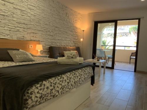 1 dormitorio con cama y pared de ladrillo en BOUTIQUE Apartment, en Los Cristianos