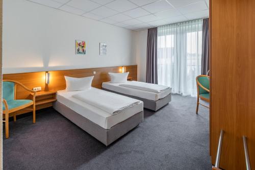 a hotel room with two beds and a desk at Center Hotel Kaiserhof in Naumburg