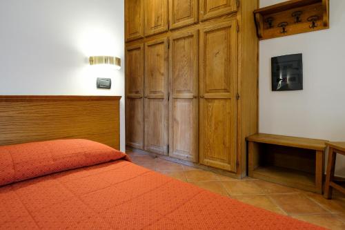 een slaapkamer met een bed en een houten kast bij Hotel Casalpina Don Barra in Pragelato