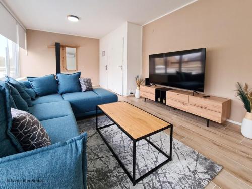 a living room with a blue couch and a flat screen tv at St. Antoni Suite 5 in Eisenstadt