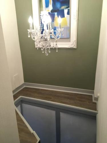 a hallway with a chandelier on a green wall at L'ancienne Forge - a stylish medieval holiday home in Confolens
