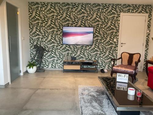a living room with a tv on a wall at Chambre d hôtes Le Joyau with indoor pool and sauna in Lasne