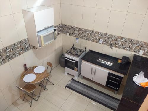 una pequeña cocina con fogones y mesa. en Kitnets casa Amarela Imbassai, en Imbassai