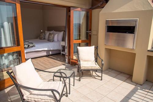 Habitación con balcón con cama y sillas. en The Golfers Villa, en Knysna