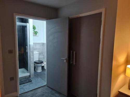 une porte ouverte menant à une salle de bains pourvue de toilettes. dans l'établissement Luxury 2 Bedroom, and 2 Bathroom Apartment, à Cardiff
